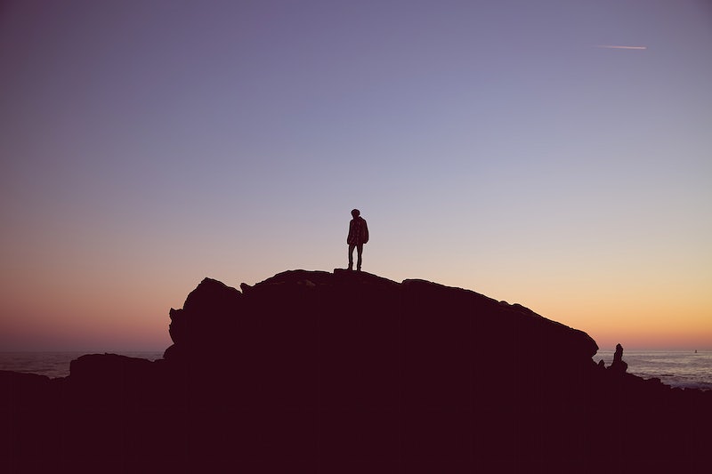 A silhouette of a person on a large rock by the sea at sunset. Original public domain image from Wikimedia Commons