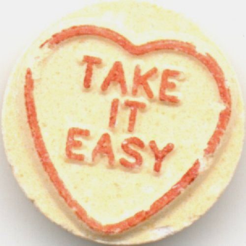 Image of a light yellow valentines candy that reads "Take it Easy" in red text inside a red heart
